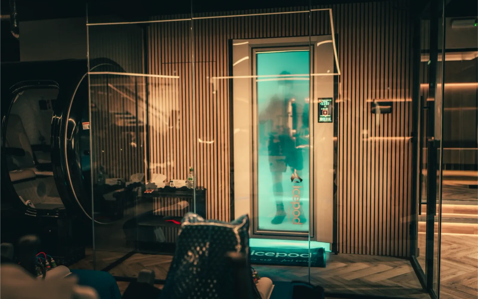 The cryotherapy chamber glowing blue behind glass at The FIT Partnership, with a member inside